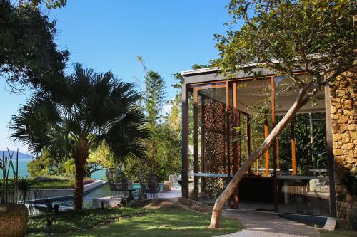 a glass house with a palm tree in the yard at Wyndham Ilhabela Casa Di Sirena in Ilhabela