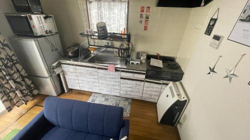 a kitchen with a blue couch and a sink and a refrigerator at ELM On The Beach in Kitaibaraki