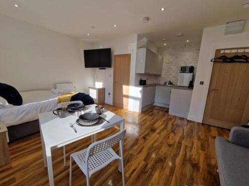 a living room with a white table and a kitchen at Flat 5. Modern studio apartment, Tynte Hotel, Mountain Ash in Quakers Yard