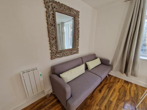 a living room with a couch and a mirror at Flat 5. Modern studio apartment, Tynte Hotel, Mountain Ash in Quakers Yard