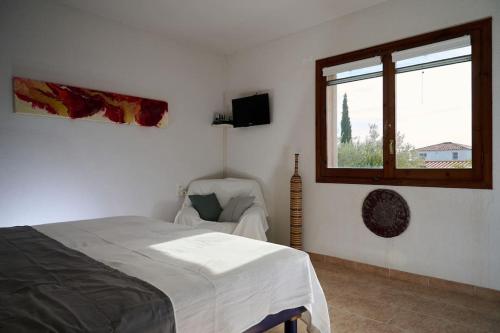 a bedroom with a bed and a window and a chair at Casa Nuria in L'Ampolla