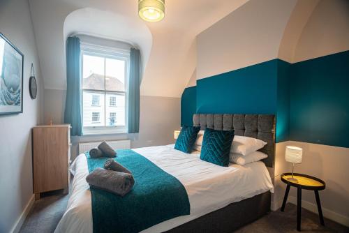 a bedroom with a bed with a blue accent wall at The Becket - Three Bedroom City Centre House with Parking in Canterbury