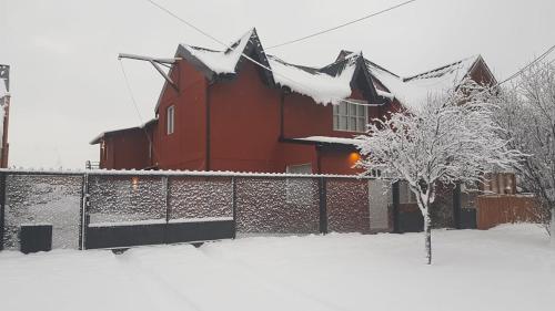 una casa roja cubierta de nieve con una valla en Vientos del Sur Esquel en Esquel