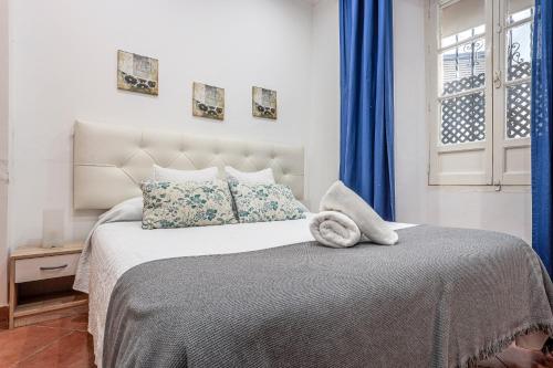 sypialnia z dużym łóżkiem i niebieskimi zasłonami w obiekcie CASA DE LA LUZ -Elegante Casco Antiguo 5-Hab w Sewilli