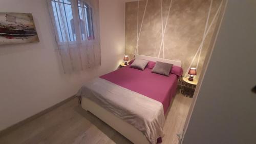 a bedroom with a bed with purple sheets and a window at Apartamento Hakuna Matata in Costa Del Silencio