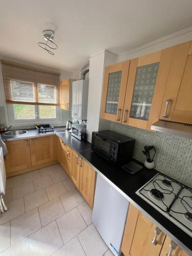 une cuisine avec des armoires en bois et un comptoir noir dans l'établissement Les Jonchères, à Luxeuil-les-Bains