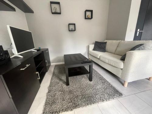 sala de estar con sofá, TV y mesa en Les Jonchères en Luxeuil-les-Bains