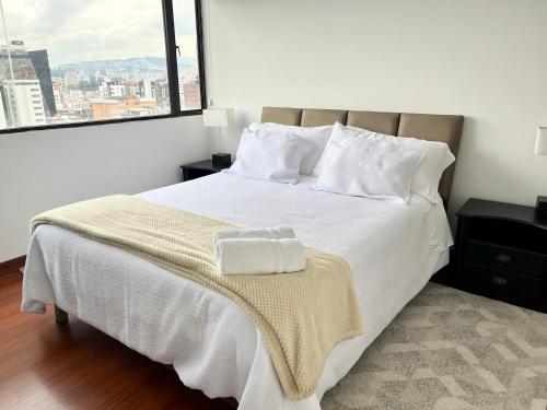 a bedroom with a white bed with a large window at Suite amoblada con aparcamiento privado excelente vista y ubicación! Sector La Carolina in Quito