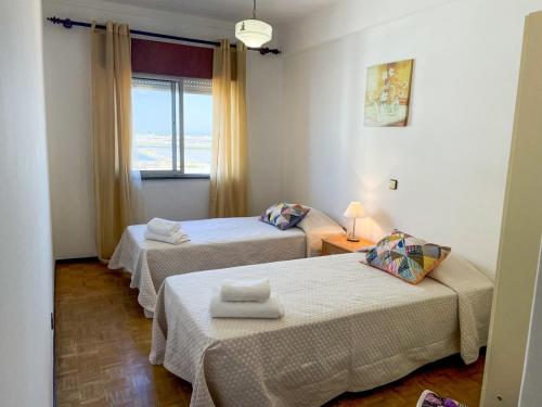 a room with two beds and a window at Cantinho dos avós in Fuzeta