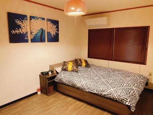 1 dormitorio con 1 cama y pinturas en la pared en 悠雅軒, en Osaka