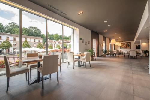 a restaurant with tables and chairs and large windows at Blau Hotel Las Caldas in Las Caldas