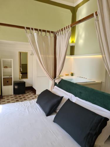 a bedroom with a white bed with a green canopy at Toscano Palace Luxury Rooms Catania in Catania