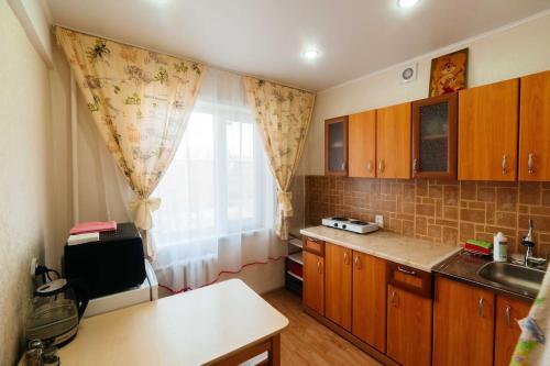 a kitchen with wooden cabinets and a window with a sink at Светлая и уютная в центре in Pavlodar