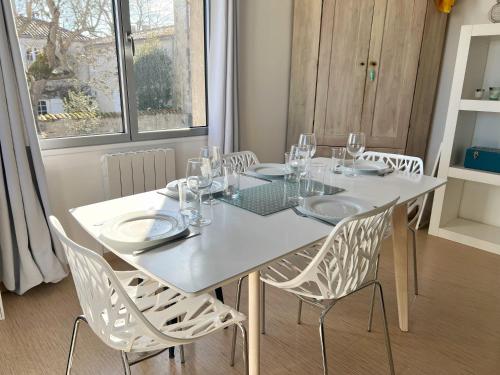 ein weißer Esstisch mit Stühlen sowie ein weißer Tisch und ein Chairsktop in der Unterkunft La Petite Échappée - Proche mer in La Genilliere