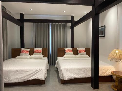 a bedroom with two beds with white sheets and red pillows at Lotus Beach House in Phan Thiet