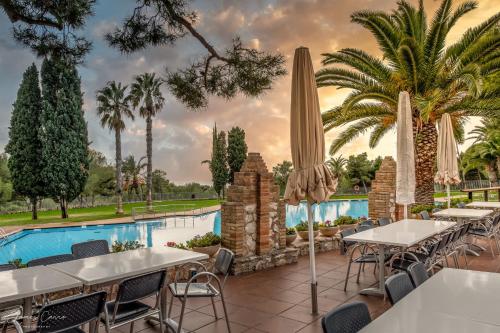 Un restaurante con mesas y sombrillas junto a una piscina. en Camping Vilanova Park, en Vilanova i la Geltrú