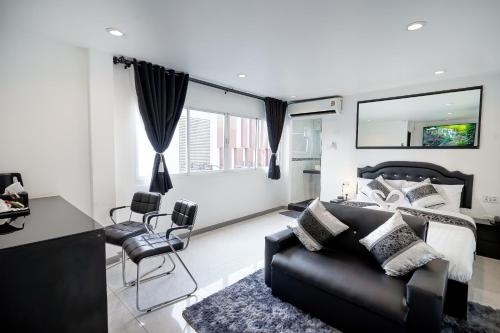 a living room with a black couch and a bed at Thonglor Suites Hotel in Bangkok
