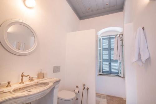 a bathroom with a sink and a mirror and a toilet at The Anchor House in Symi