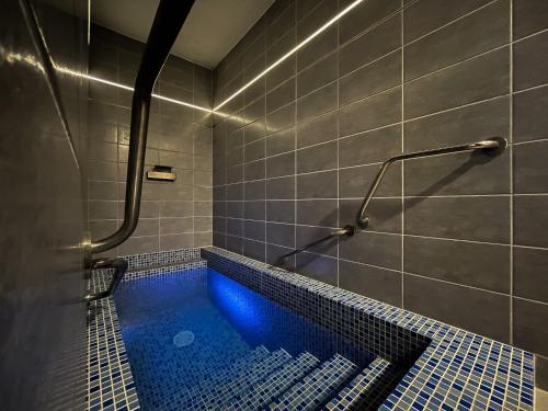 La salle de bains est pourvue d'une douche avec une baignoire bleue. dans l'établissement Hotel Aldo, à Uničov