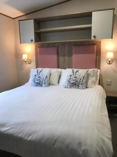 um quarto com uma cama grande com lençóis brancos e almofadas em 41 Lade Links St Andrews Holiday Park em St. Andrews