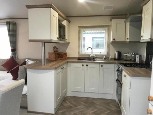 uma cozinha com armários brancos e um forno com placa de fogão em 41 Lade Links St Andrews Holiday Park em St. Andrews