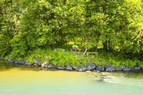 a person sitting on a picnic table next to a river at Gasthof Wagner Restaurant-Pension in Halbenrain