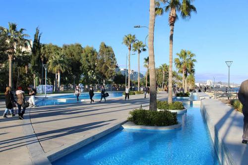 a group of people walking in a street with palm trees at Sea Breeze Central, 2bed in Limassol