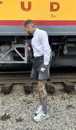 um homem com uma tatuagem na perna ao lado de um comboio em Menlo gate 768 em Pretoria