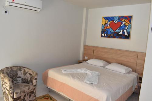 1 dormitorio con 1 cama, 1 silla y 1 pintura en Rai Hotel - By UP Hotel - próximo a Prefeitura, en Cascavel