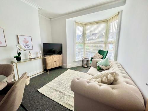 uma sala de estar com um sofá e uma televisão em Stunning Flat Close to Beach em Swansea