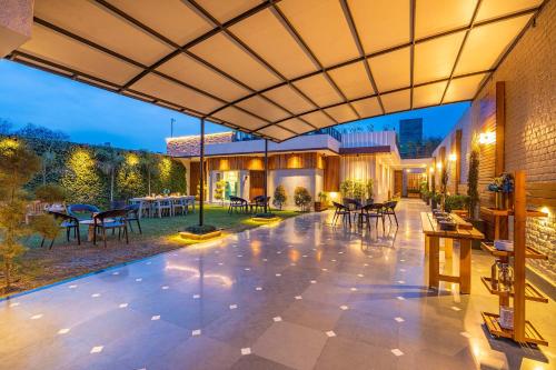 an outdoor patio with tables and chairs and a building at D Amour by VEO - Part of StayVista in Amritsar