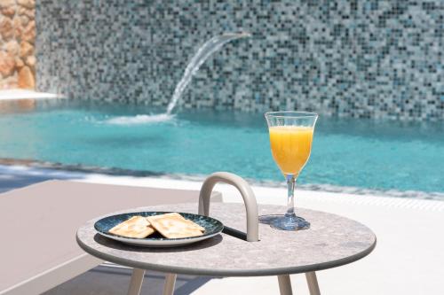 a glass of orange juice and crackers on a table next to a pool at Seashell Luxury Residence - Apartment 1 in Lixouri