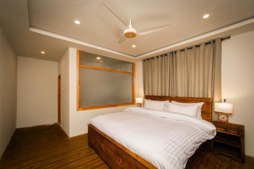 a bedroom with a large white bed with a window at Roomy Daastaan Hotel, Karimabad Hunza in Hunza