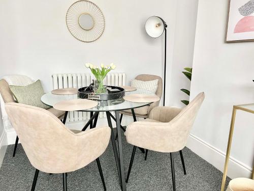 a dining room with a glass table and chairs at Stunning Flat Close to Beach in Swansea