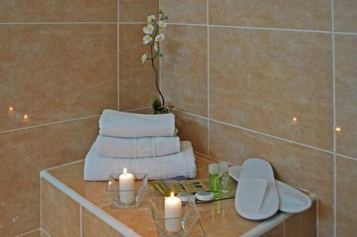 El baño incluye una mesa con velas y toallas. en Hotel Piccadilly Sitges en Sitges