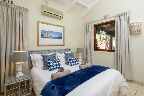 Un dormitorio con una cama con almohadas azules y blancas. en San Lameer Villa 2007 - 1 Bedroom Classic - 4 pax - San Lameer Rental Agency, en Southbroom