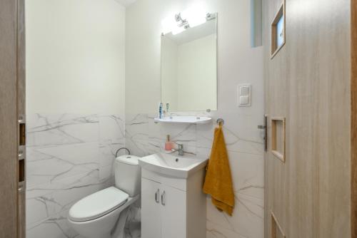 Baño blanco con aseo y lavamanos en Villa Oliva, en Gdansk