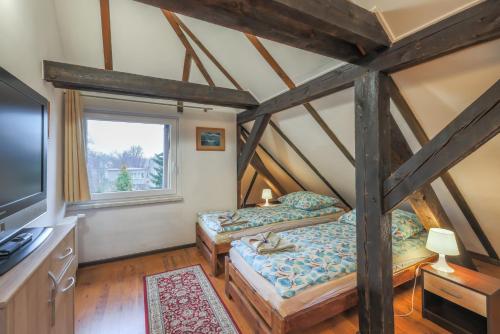 two beds in a room with a tv and a window at Villa Oliva in Gdańsk