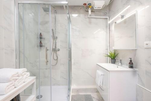 La salle de bains blanche est pourvue d'une douche et d'un lavabo. dans l'établissement Bohemian Flat - Lovely Marais, à Paris