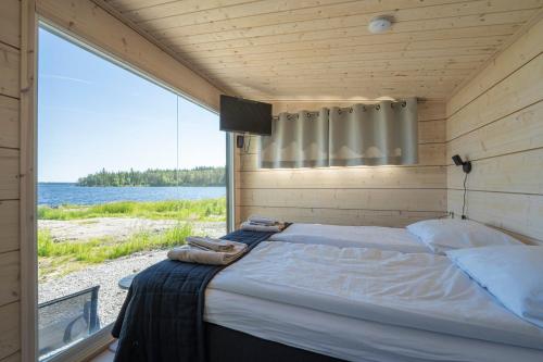 Schlafzimmer mit einem Bett und Blick auf das Wasser in der Unterkunft Loma Luonnonlapsi Tuli-mökki in Sotkamo