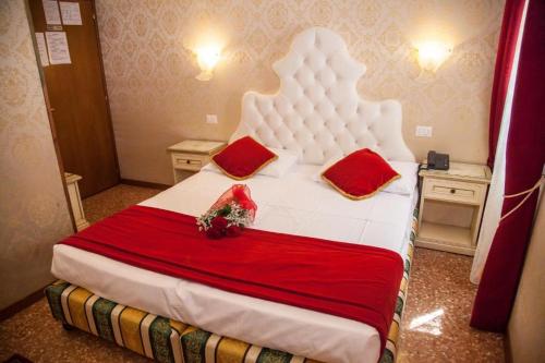 a bedroom with a large white bed with red pillows at Residenza La Campana in Venice