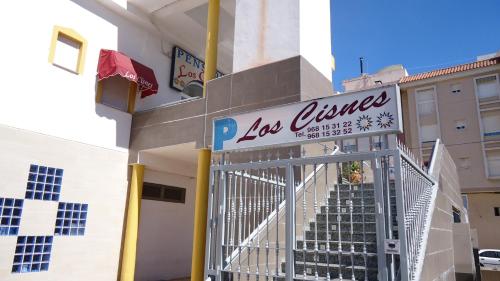 a building with a gate with a sign for los angeles at Pension Los Cisnes in Puerto de Mazarrón