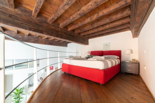 a bedroom with a red bed and a wooden ceiling at Guelfi loft in a historic palace in Florence
