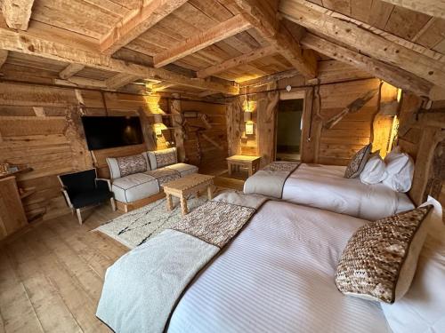 a bedroom with two beds in a log cabin at Hotel Xaluca Spa Aguelmame Sidi Ali in Aguelman