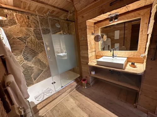 a bathroom with a shower and a sink and a mirror at Hotel Xaluca Spa Aguelmame Sidi Ali in Aguelman