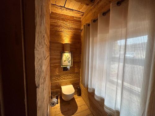 a wooden bathroom with a toilet and a window at Hotel Xaluca Spa Aguelmame Sidi Ali in Aguelman