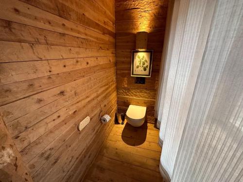 a bathroom with a toilet and a wooden wall at Hotel Xaluca Spa Aguelmame Sidi Ali in Aguelman