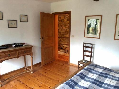 een slaapkamer met een bed, een bureau en een houten deur bij Le Moulin des Aulnes in Hamois