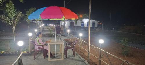 a man sitting at a table under an umbrella at Govind Niwas Homestay in Jagdalpur