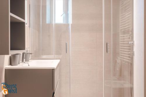 uma casa de banho branca com um chuveiro e um lavatório. em Michael&Renate - Stylish studio em Trieste